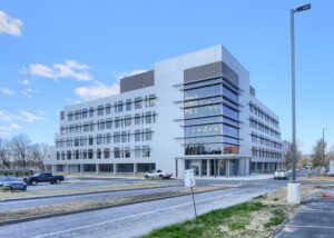 Modern five-story commercial office building with sleek glass and metal facade at 225 Grandview Avenue, featuring large windows, ample parking, and contemporary architectural design under a bright blue sky.