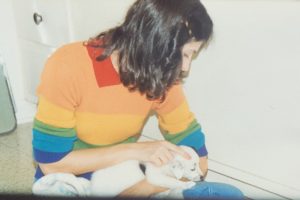 A woman holding a white puppy on her lap